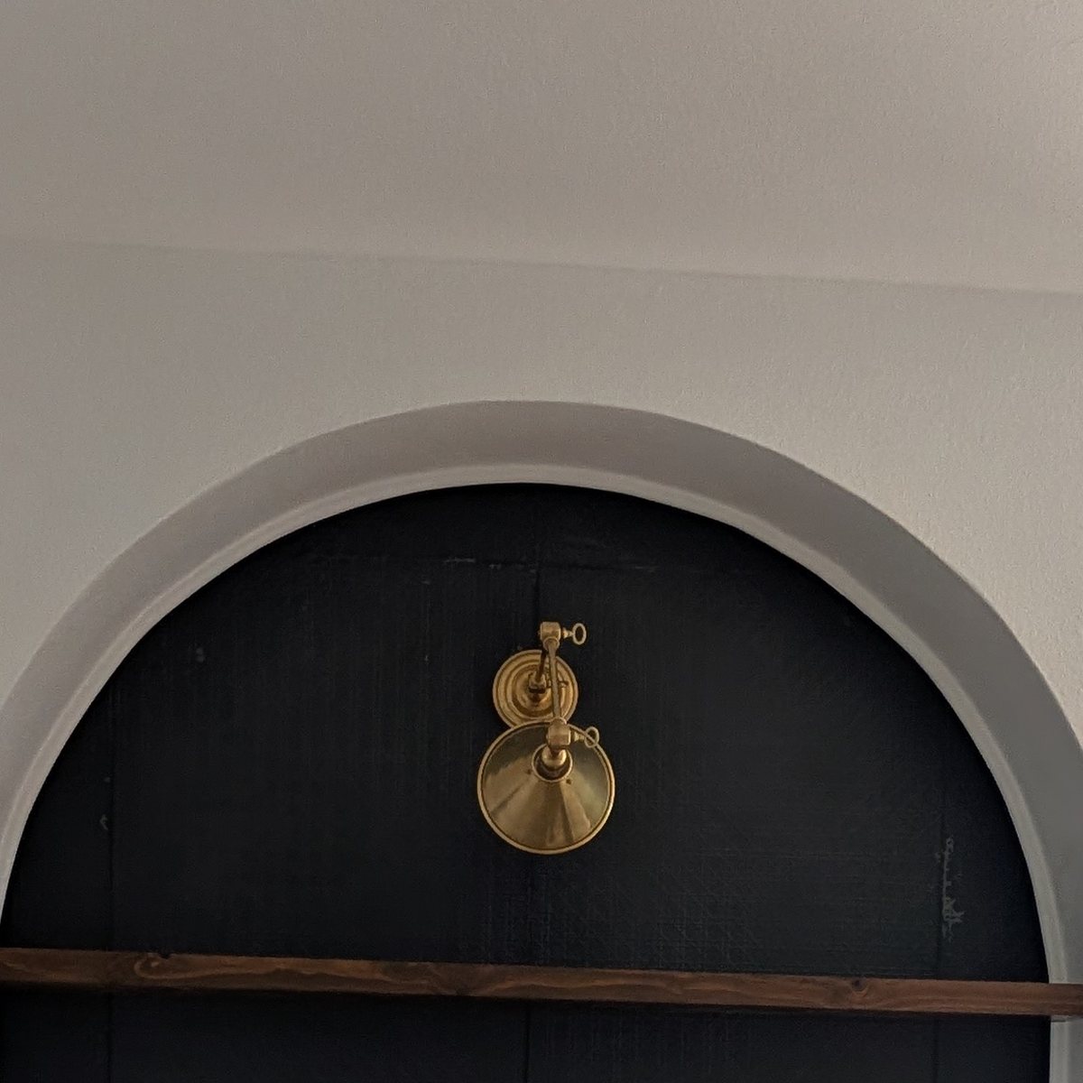 Built-in cabinetry beside an arched niche painted near-black