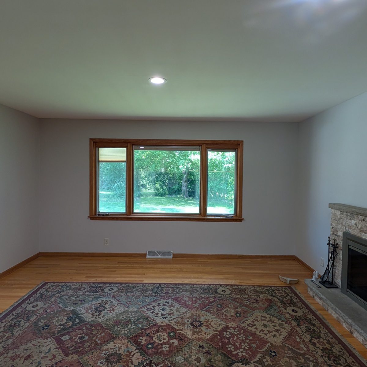 Living room repainted around a stone fireplace and wood window trim