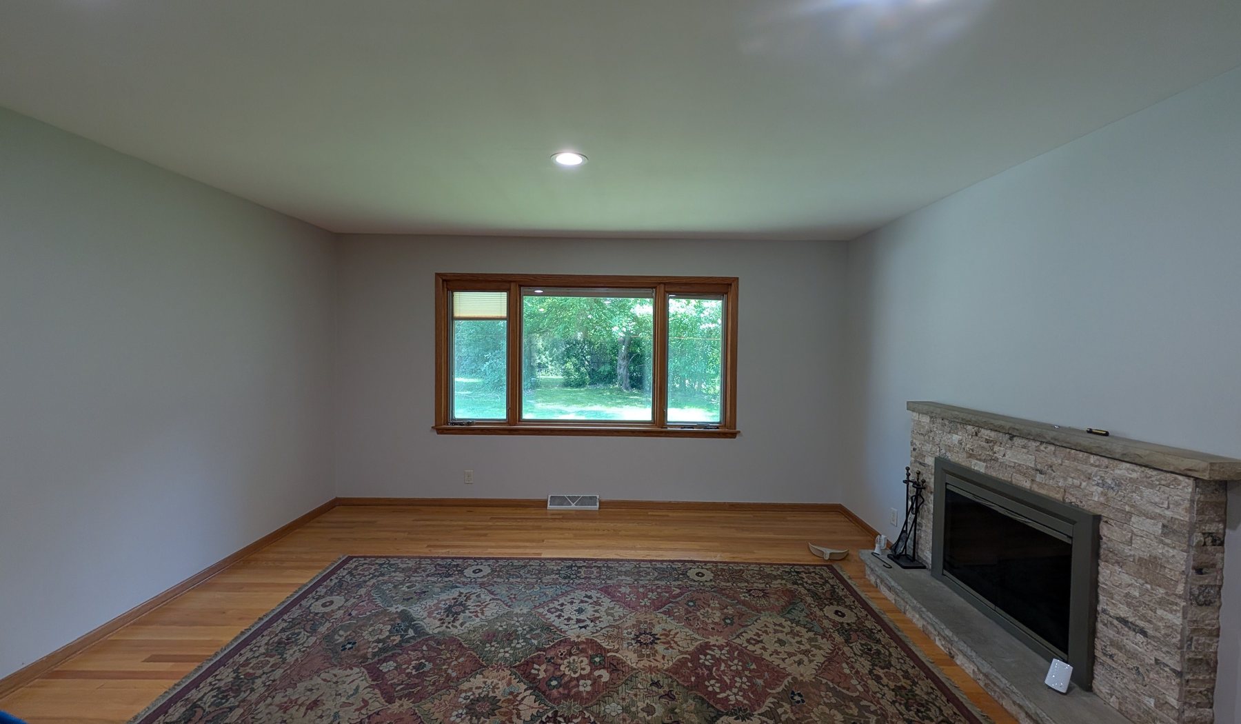 A repainted living room with a stone fireplace and refinished wood trim